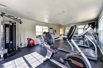A home gym with a treadmill, weights, and exercise equipment.